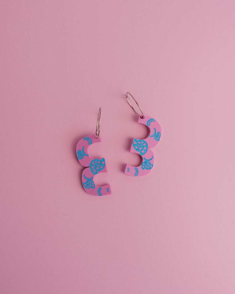 MISS MAIA, May 2022. A flatlay pic of the Pink and Blue Kōtuitui I earrings on a pink background.