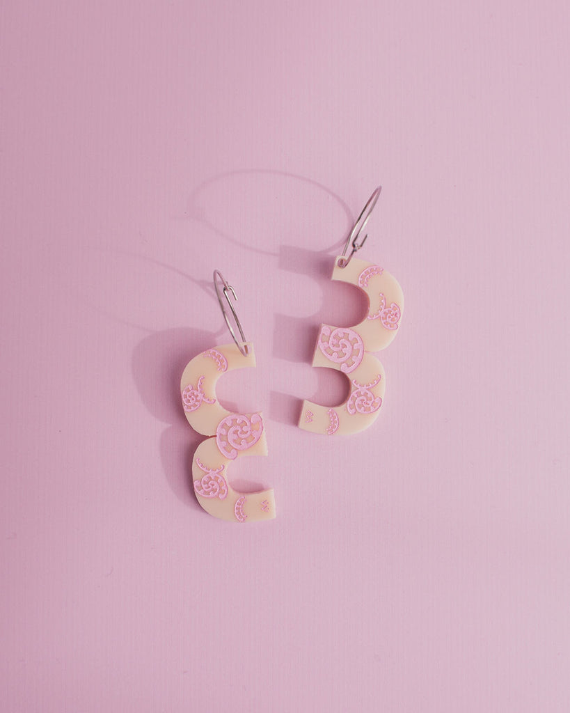 MISS MAIA, May 2022. A flatlay pic of the Ivory and Pink Kōtuitui I earrings on a pink background.