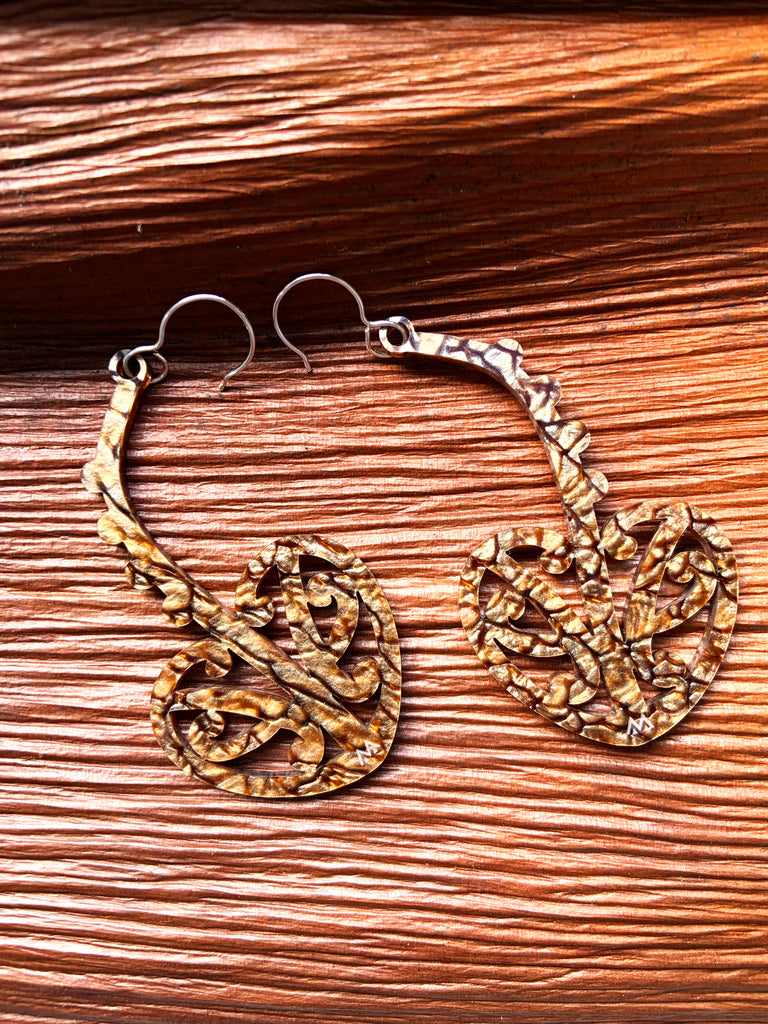 MISS MAIA Pāhautea earrings in Bronze Coral sits on top of a nikau bark.
