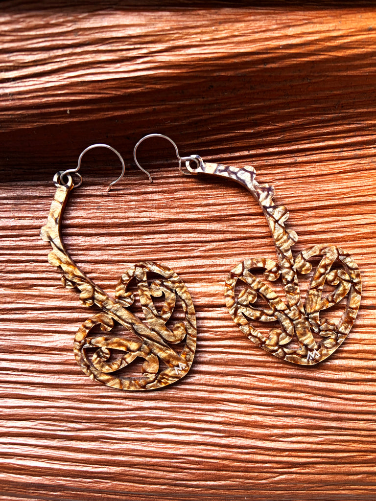 MISS MAIA Pāhautea earrings in Bronze Coral sits on top of a nikau bark.